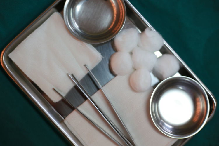 Directly above shot of cotton balls and equipment with bowls in tray on table in hospital