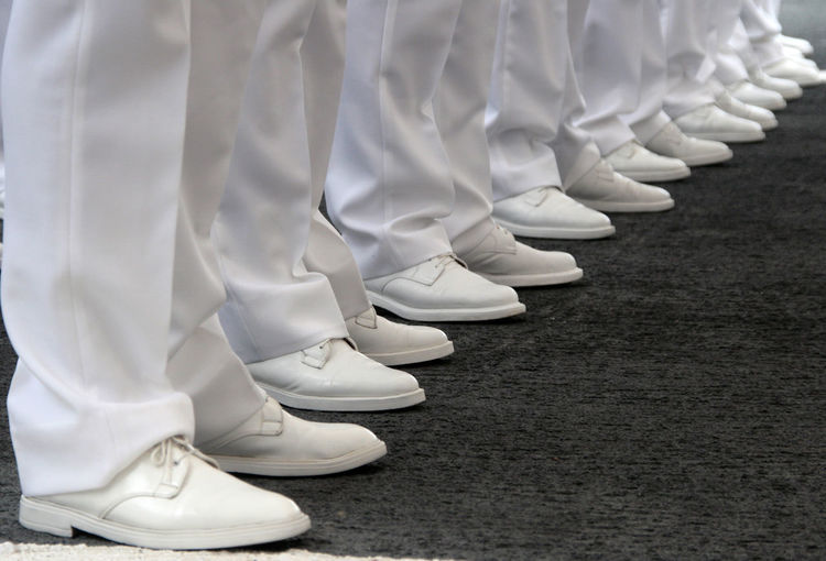 Legs in formation of navy officers white vests and white shoes in perspective
