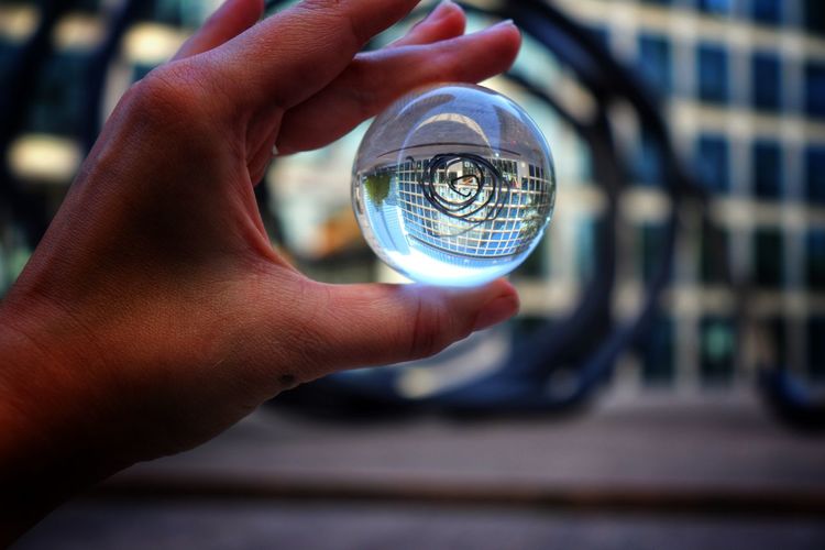 Low angle view of hand holding crystal ball