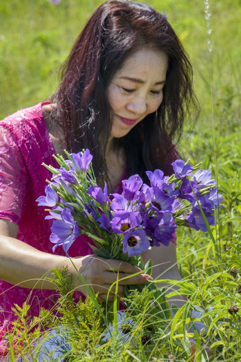 Close-up of woman with purple flowers on field