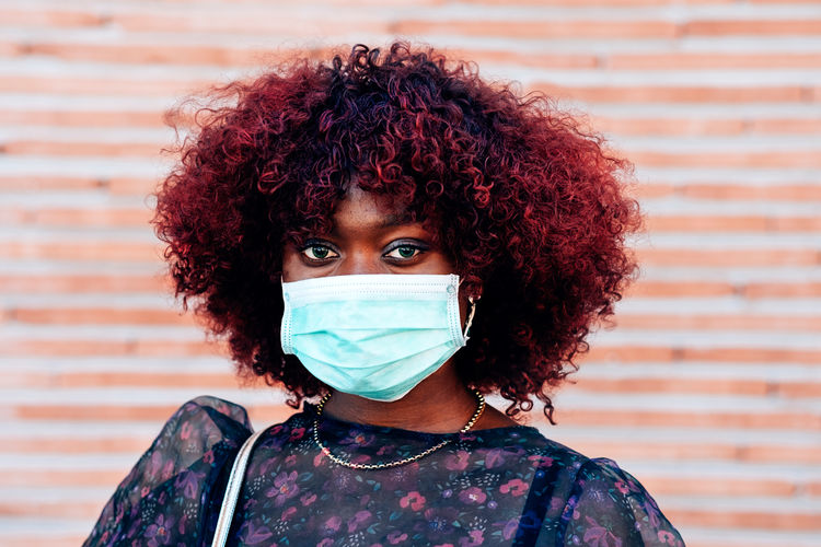 Close up portrait of young black woman wearing face medical mask to prevent coronavirus infection
