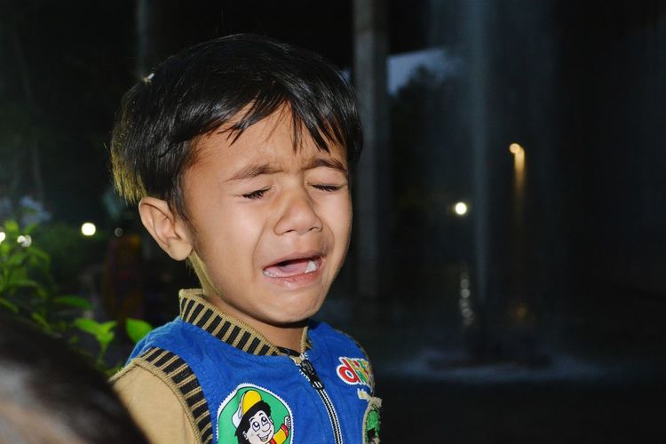 Close-up of boy crying at night