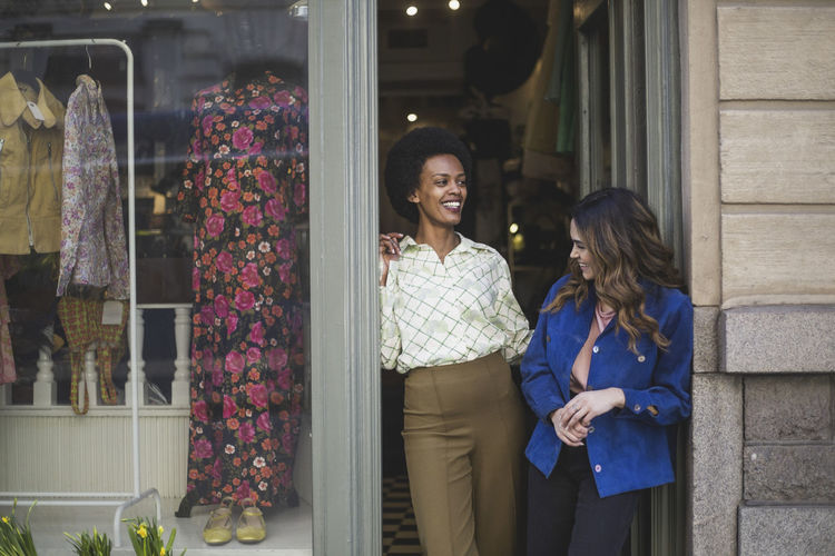 Female entrepreneurs laughing while talking with each other at clothing store