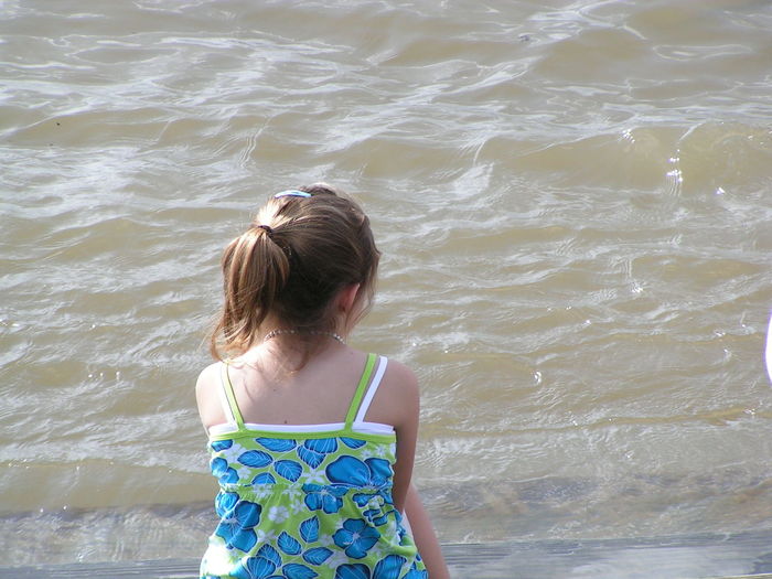 Rear view of girl sitting by sea