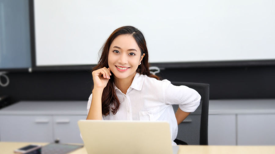 Young businesswoman using mobile phone while sitting in office