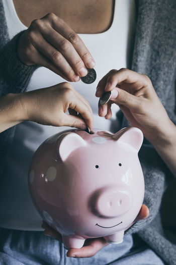 Close-up hands putting coin in happy smiling piggy bank. people saving money for household payments