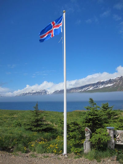 Icelandic flag against calm blue lake and sky