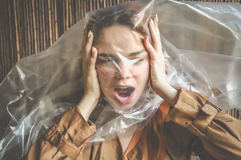 Frustrated young woman with plastic on face shouting 