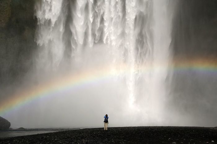 Tourist enjoying the view of waterfall and rainbow
