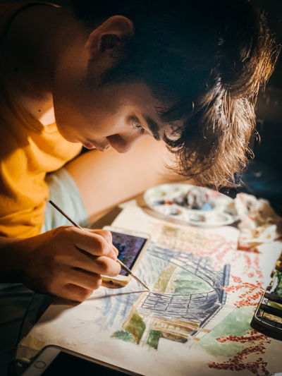 Man drawing on canvas while sitting at home