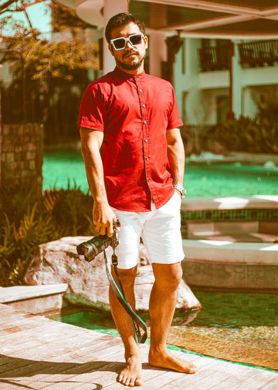 Full length of young man standing by swimming pool