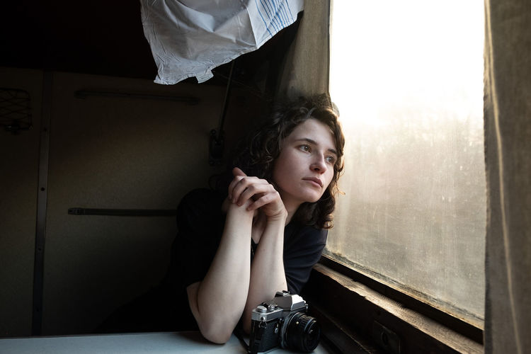 Portrait of young woman sitting on bed at train 