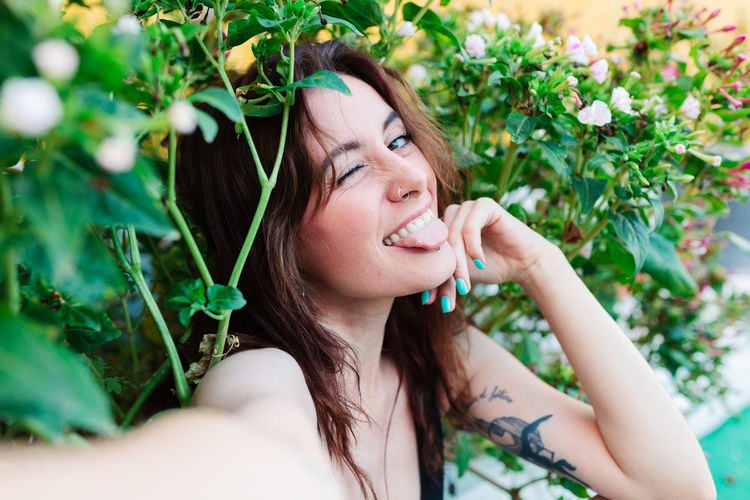 Portrait of young woman with eyes closed against plants