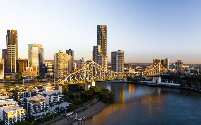 Bridge over river and buildings against clear sky