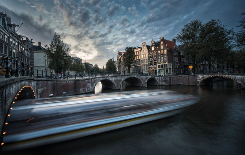 Bridge over canal in city against sky