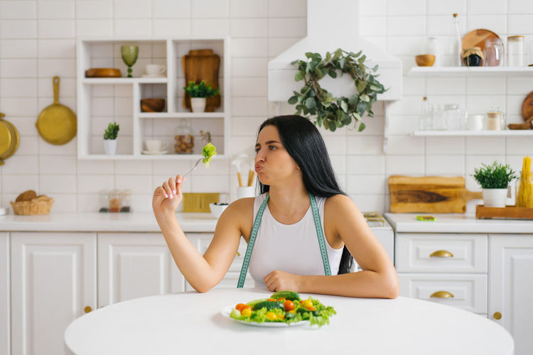 Disgruntled woman is going to eat healthy food in the form of vegetables in the kitchen person