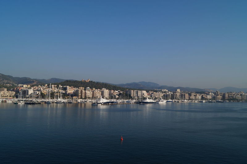 View of townscape by sea against clear blue sky