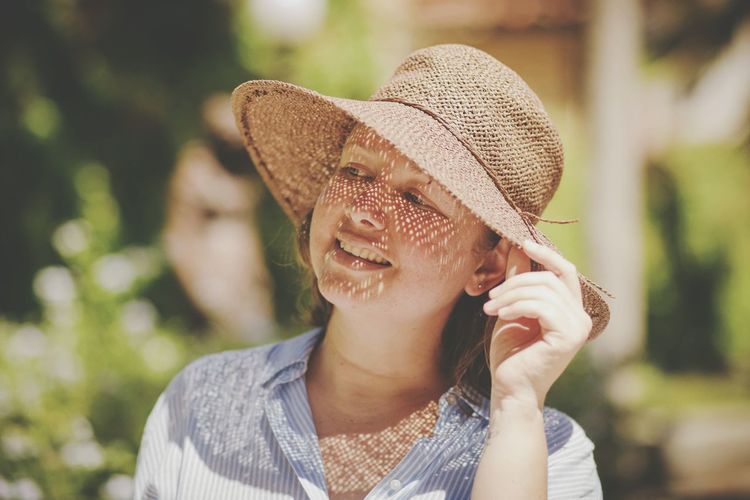 Close-up of mid adult woman wearing hat while standing at park