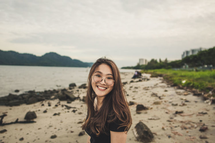 Side view portrait of cheerful woman standing at beach