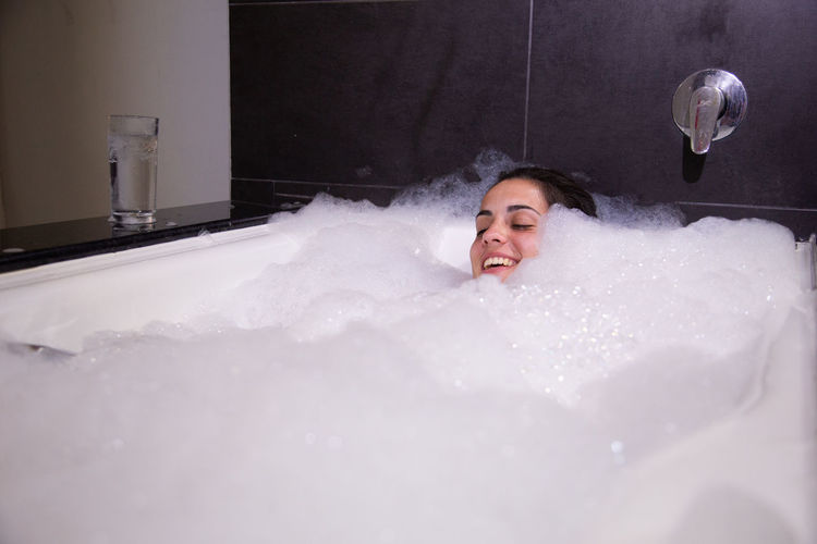 Young woman taking bubble bath in bathtub
