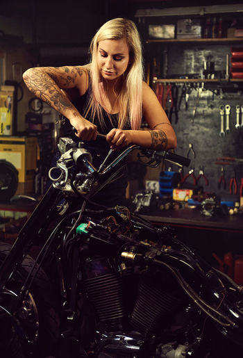 Full length of woman with repairing a motorbike