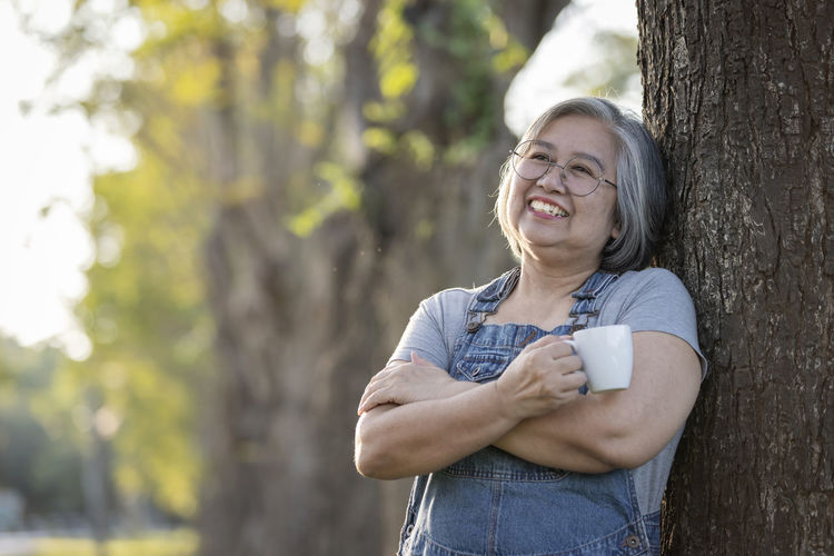 Portrait of young woman sitting on tree trunk
