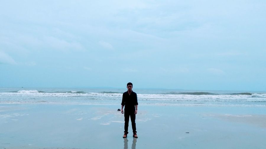 Full length of man standing at beach against sky
