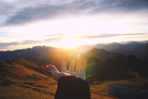 Hand outstretched towards scenic view of mountains