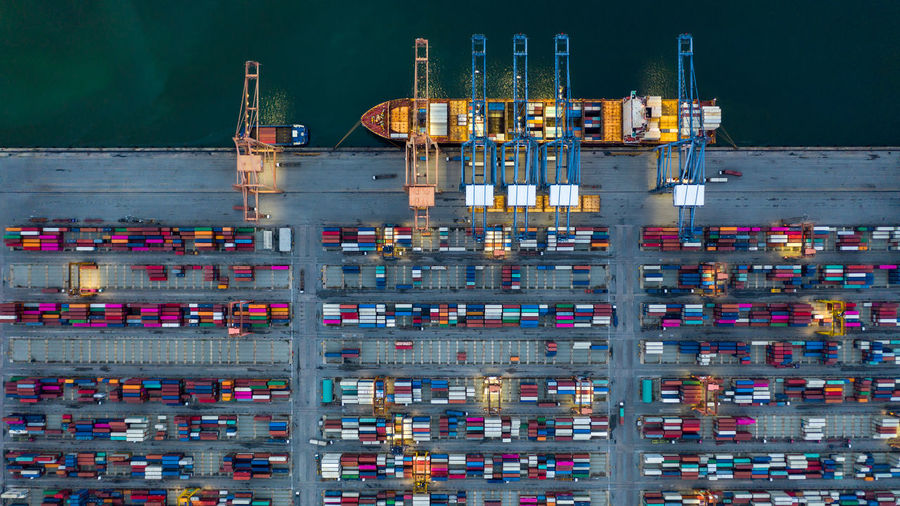 Aerial view container ship loaded in container terminal at night, global business import export 