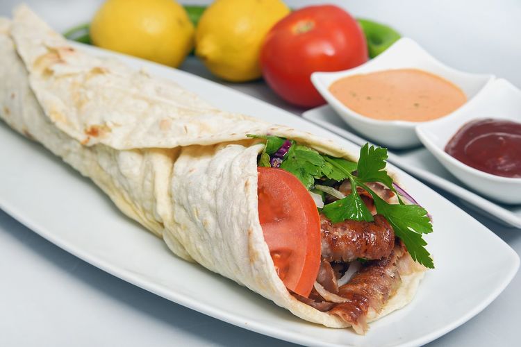 Close-up of fresh kebab shawarma served in plate with savory sauces