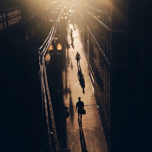 People walking on sidewalk in city at sunset