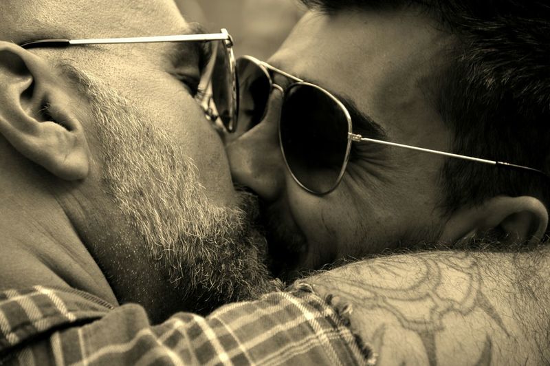 Close-up of gay men wearing sunglasses kissing on mouth