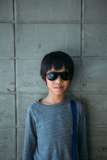 Portrait of boy in sunglass standing against wall