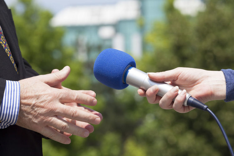 Cropped hand holding microphone by businessman during interview
