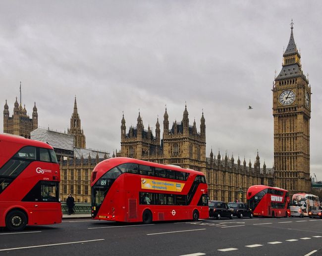 Bus passing by big ben against cloudy sky