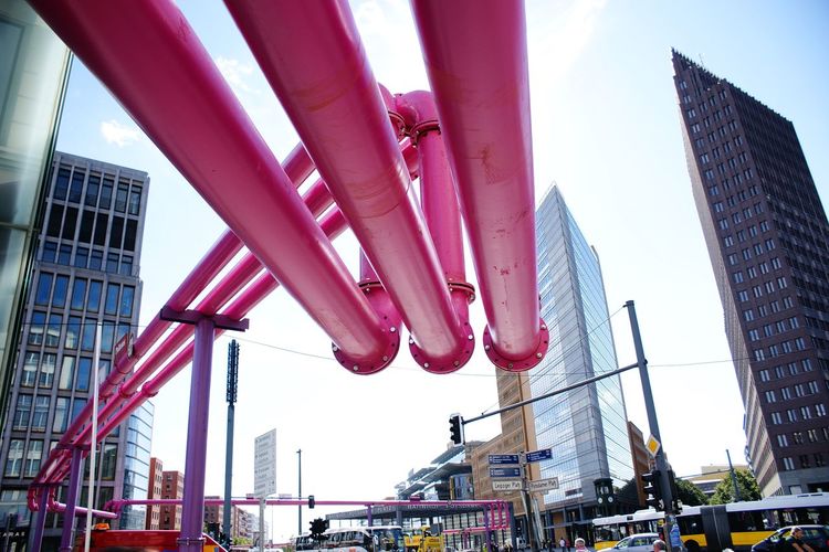 Low angle view of red pipes against buildings in city