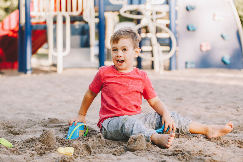 Cute boy playing while sitting on sand