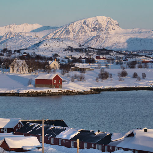Buildings by lake against sky during winter