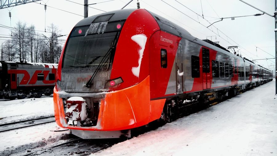 Modern trains at snow covered field against sky
