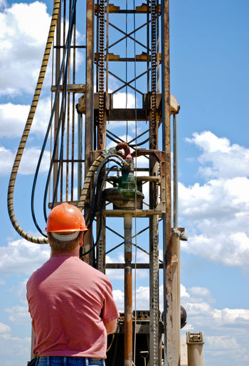 An oil worker watches a rig drilling a new well