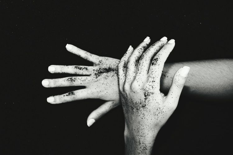 Cropped messy hands of woman against black sand
