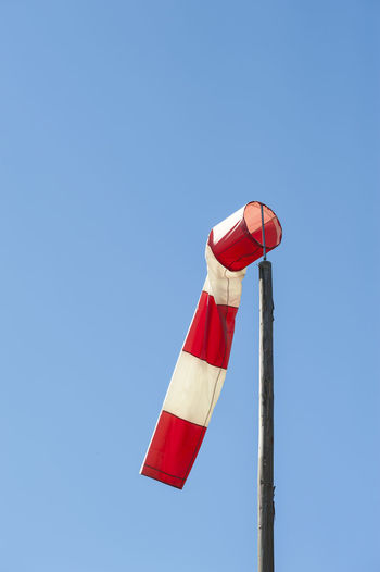 Low angle view of windsock against clear blue sky