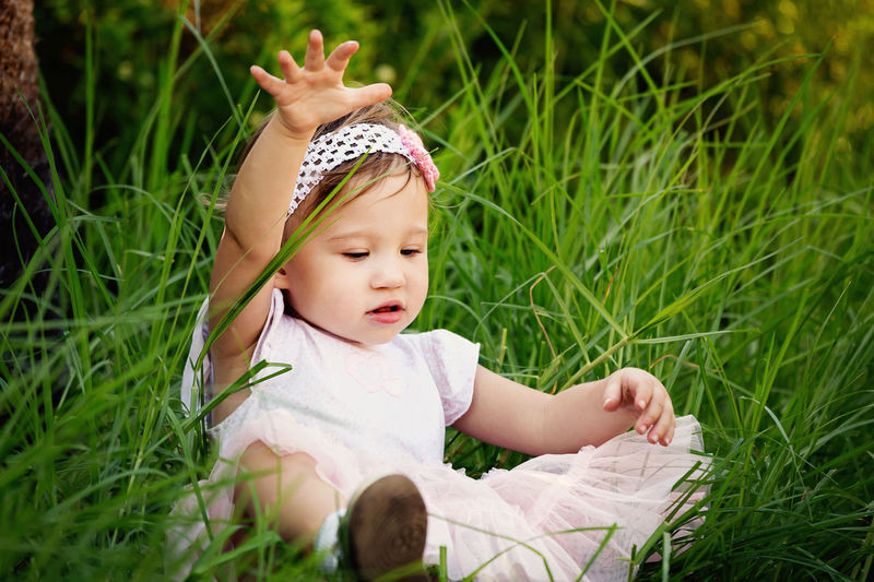 Close-up of cute girl sitting on grassy field