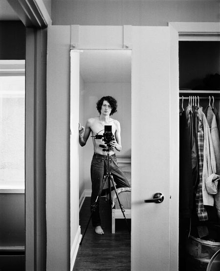 Reflection of shirtless man photographing on mirror at home