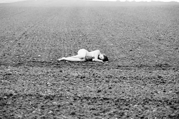 Naked woman lying on field
