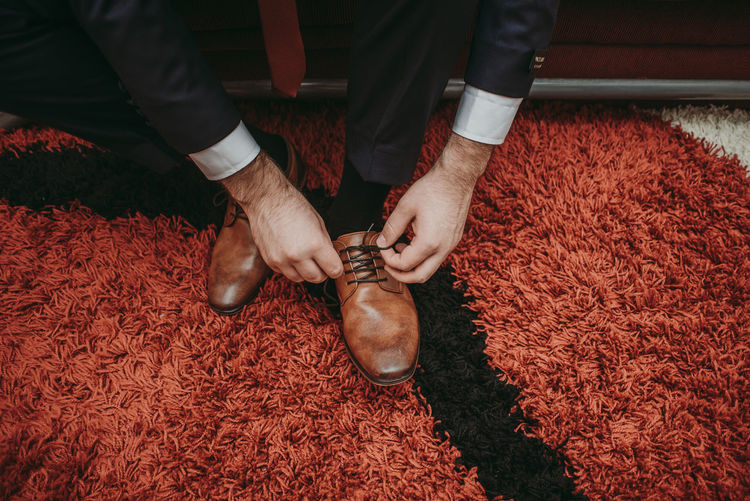 Groom tying wedding brown shoes