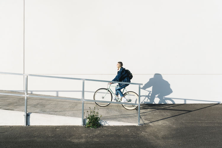 Man riding bicycle on railing against wall