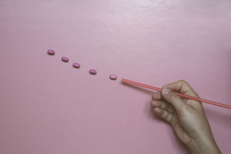 Cropped hand holding drinking straw by candies over table