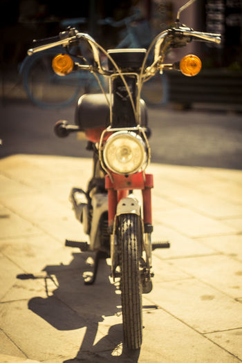 Close-up of moped parked on street during sunny day