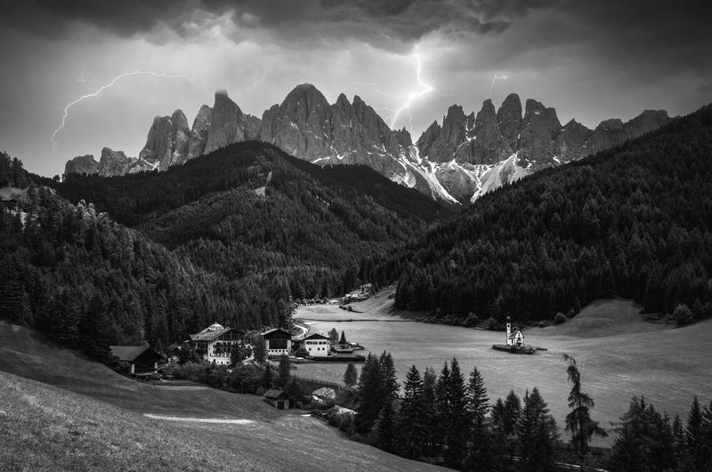 Dramatic image of majestic mountains and lightning in saint magdalena village in dolomites, italy